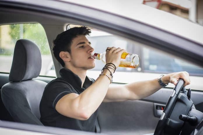 homme boit de l'alcool en conduisant
