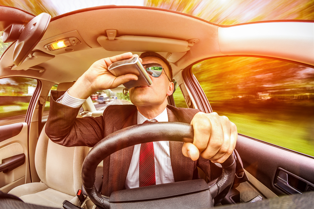 homme buvant de l'alcool en conduisant